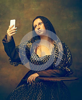 Young woman as Mona Lisa on dark background. Retro style, comparison of eras concept.