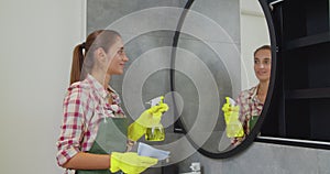 Young woman as a professional cleaner in uniform cleaning bathroom. Cleaning service concept.