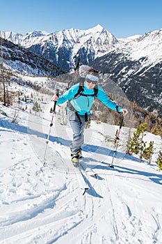 Young woman ascending a slope on skis.