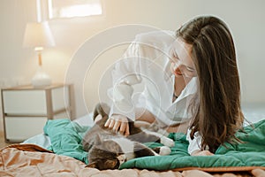 Young woman asia wake up refreshed in the morning playing with cats at bed happily on holiday.