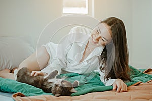 Young woman asia wake up refreshed in the morning playing with cats at bed happily on holiday.