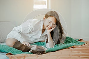 Young woman asia wake up refreshed in the morning playing with cats at bed happily on holiday.