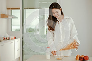 Young woman asia wake up refreshed in the morning and relaxing eat coffee, cornflakes, bread and apple for breakfast at house on h