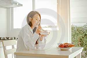 Young woman asia wake up refreshed in the morning and relaxing eat coffee, cornflakes, bread and apple for breakfast at house on h