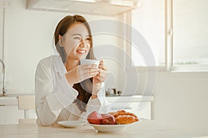 Young woman asia wake up refreshed in the morning and relaxing eat coffee, cornflakes, bread and apple for breakfast at house on h