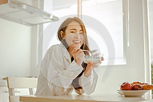 Young woman asia wake up refreshed in the morning and relaxing eat coffee, cornflakes, bread and apple for breakfast at house on h