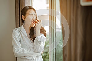 Young woman asia wake up refreshed in the morning and relaxing eat coffee, cornflakes, bread and apple for breakfast at house on h