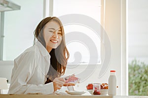 Young woman asia wake up refreshed in the morning and relaxing eat coffee, cornflakes, bread and apple for breakfast at house on h