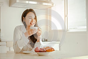 Young woman asia wake up refreshed in the morning and relaxing eat coffee, cornflakes, bread and apple for breakfast at house on h