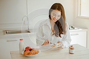 Young woman asia wake up refreshed in the morning and relaxing eat coffee, cornflakes, bread and apple for breakfast at house on h