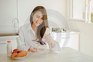 Young woman asia wake up refreshed in the morning and relaxing eat coffee, cornflakes, bread and apple for breakfast at house on h