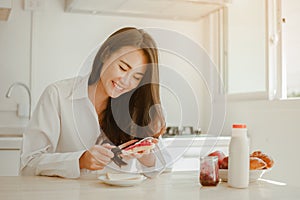 Young woman asia wake up refreshed in the morning and relaxing eat coffee, cornflakes, bread and apple for breakfast at house on h