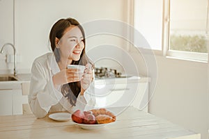 Young woman asia wake up refreshed in the morning and relaxing eat coffee, cornflakes, bread and apple for breakfast at house on h