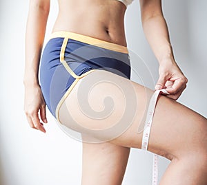 Young woman asian measuting her thigh with a measuring tape