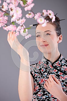 Young woman in asian outfit touching flower