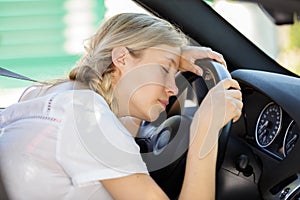 young woman asleep slumped over wheel car
