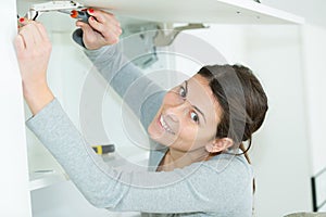 young woman assembling cupboard at home