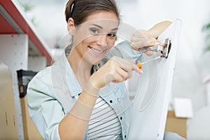 young woman assembling cupboard at home