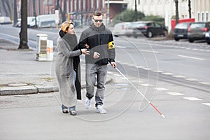 Woman Assisting Blind Man On Street photo