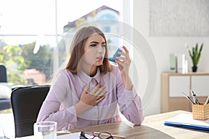 Young woman with asthma inhaler at tabl
