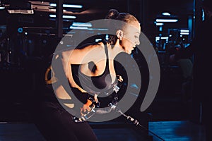 Young woman athlete with an active lifestyle pulls on the training appliance for the arms, chest and back