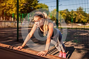 Young woman athlete doing push-ups on sportsground in summer. Healthy lifestyle