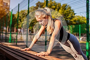 Young woman athlete doing push-ups on sportsground in summer. Healthy lifestyle