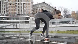 Young woman athlete sprinting in front of camera on a run path running athletic track. 120fps