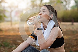 Young woman athlete takes a break, drinking water, out on a run on a hot day.