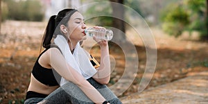 Young woman athlete takes a break, drinking water, out on a run on a hot day.