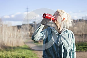 Young woman athlete takes a break, drinking water, out on a run on a hot day