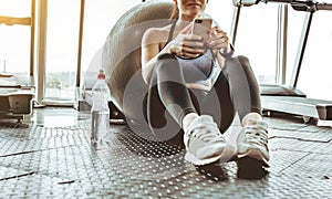Young woman athlete using cell phone at gym.