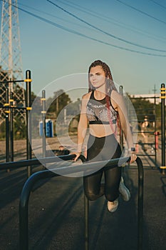 A young woman of athletic physique is doing an exercise on the uneven bars