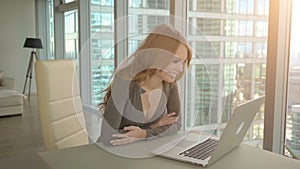 Young woman attending video conference from home using laptop