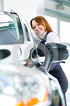 Young woman with auto in car dealership