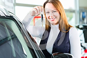 Young woman with auto in car dealership