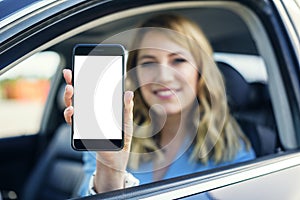Young woman in auto shows smartphone with blank screen.