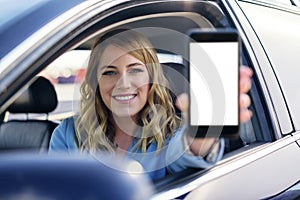 Young woman in auto shows smartphone with blank screen.