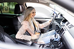 Young woman in an autonomous self driving car and drink a coffee on the highway