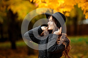 Young woman with autumn leaves in hand and fall yellow maple gar