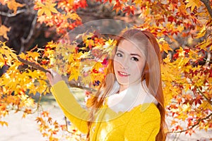 Young woman with autumn leaves in maple garden.