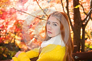 Young woman with autumn leaves in maple garden.