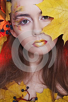 Young woman with autumn make up and leaves on head