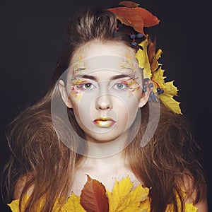 Young woman with autumn make up and leaves on head