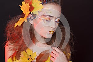 Young woman with autumn make up and leaves on head