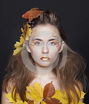 Young woman with autumn make up and leaves on head