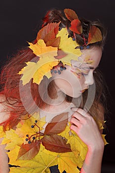 Young woman with autumn make up and leaves on head