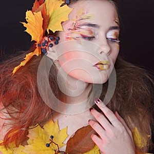 Young woman with autumn make up and leaves on head and her body