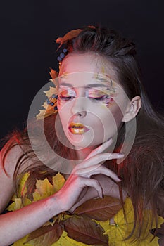 Young woman with autumn make up and leaves on head and her body