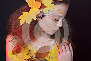 Young woman with autumn make up and leaves on head and her body